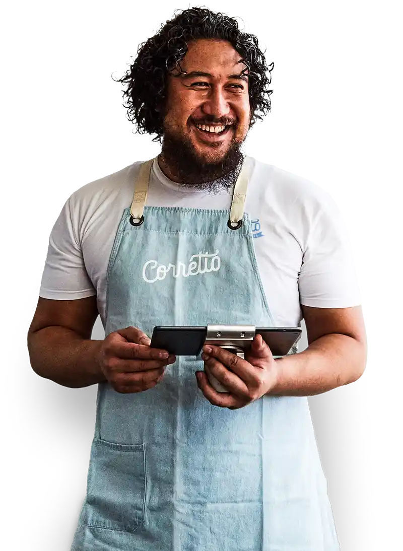 Ein lächelnder Restaurantbesitzer in einem weißen T-Shirt und einer Markenschürze verwendet Lightspeed Restaurant auf einem Tablet.