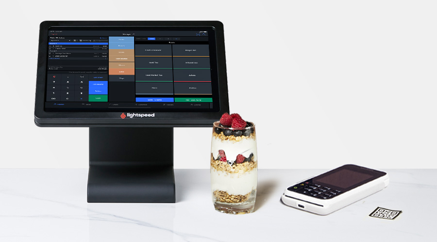 Vor weißem Hintergrund steht ein iPad mit Lightspeed Kassensystem, daneben liegt das dazugehörige Zahlungsterminal.